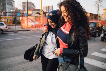 Junge Frau im Hidschab und beste Freundin gehen und reden in der Stadt - CUF52838