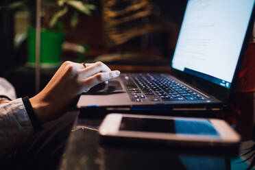 Women at cafe table typing on laptop, close up - CUF52857