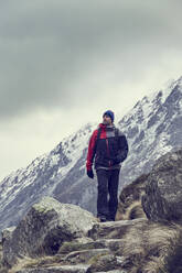 Männlicher Wanderer beim Wandern in zerklüfteter Landschaft mit schneebedeckten Bergen, Llanberis, Gwynedd, Wales - CUF52862