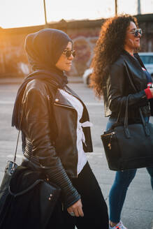 Junge Frau im Hidschab und beste Freundin spazieren in der Stadt - CUF52867