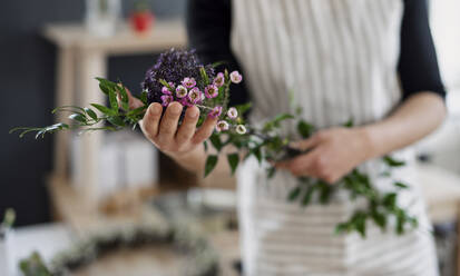 Close-up of woman holding flowers in a small shop - HAPF03028