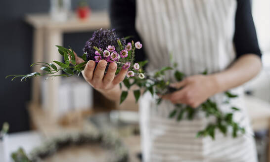 Nahaufnahme einer Frau mit Blumen in einem kleinen Laden - HAPF03028