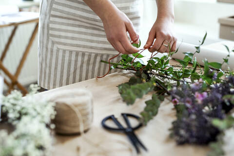 Nahaufnahme einer Frau beim Arrangieren von Blumen in einem kleinen Laden, lizenzfreies Stockfoto