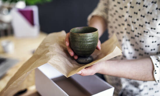 Close-up of woman wrapping an earthenware mug - HAPF03073