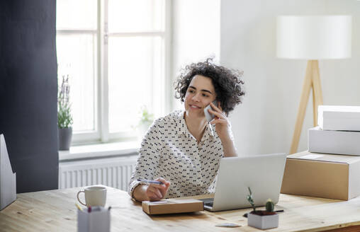 Lächelnde junge Frau am Telefon im Home Office - HAPF03080