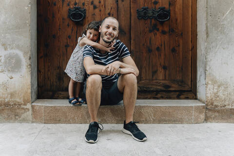 Porträt eines glücklichen kleinen Mädchens, das seinen Vater im Freien umarmt, Mallorca, Spanien, lizenzfreies Stockfoto