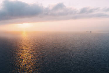 Frachtschiff, das dem Sonnenuntergang am Horizont entgegenfährt, Mallorca, Spanien - GEMF03251