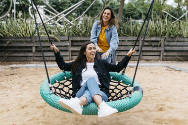 Two friends on playground, woman on a swing - JRFF03811