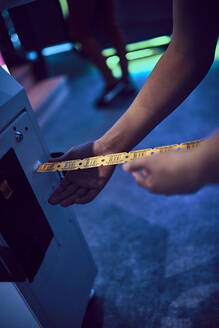 Nahaufnahme eines Teenagers, der in einer Spielhalle Tickets aus einem Automaten zieht - ZEDF02688