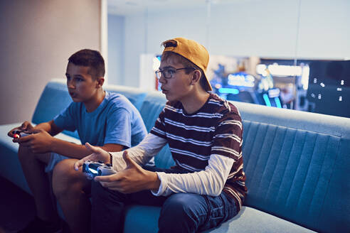 Teenage friends playing video game in an amusement arcade - ZEDF02696