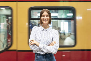 Junge Frau am Bahnhof mit unscharfem Zug als Hintergrund - WPEF02164