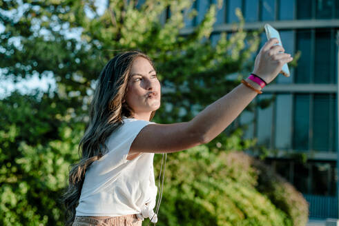 Junge Frau, die ein Selfie mit ihrem Smartphone macht, schmollender Mund - KIJF02683