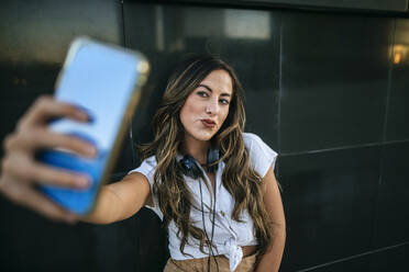 Junge Frau, die ein Selfie mit ihrem Smartphone macht, schmollender Mund - KIJF02697