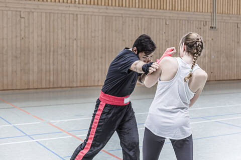 Weiblicher Boxer beim Sparring mit Trainer in der Sporthalle, lizenzfreies Stockfoto