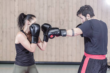 Weiblicher Boxer beim Sparring mit Trainer in der Sporthalle - STBF00479