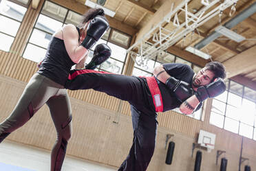 Weiblicher Kickboxer beim Sparring mit Trainer in der Sporthalle - STBF00481