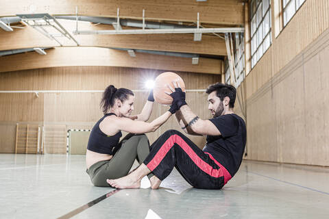 Mann und Frau beim Üben mit einem Medizinball in einer Sporthalle, lizenzfreies Stockfoto