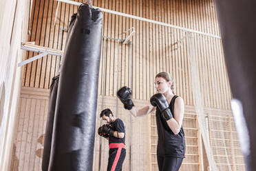 Trainer und Boxerin beim Training am Boxsack in der Sporthalle - STBF00494