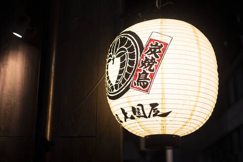 Lampion mit japanischen Buchstaben, beleuchtet bei Nacht in den Straßen von Tokio, Japan - ABZF02645