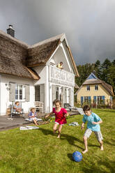 Glücklicher Bruder und Schwester spielen Fußball im Garten - EGBF00387