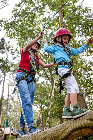 Mutter und Tochter auf einem Hochseilgarten im Wald, lizenzfreies Stockfoto