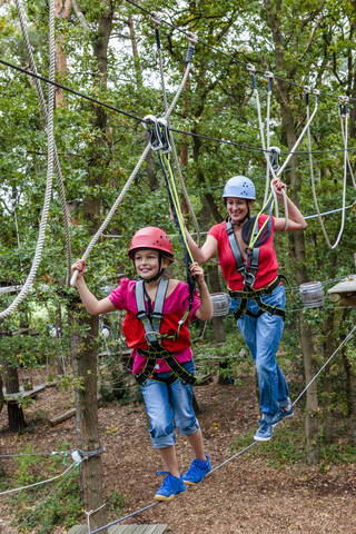 Mother and daughter on a high rope course in forest stock photo