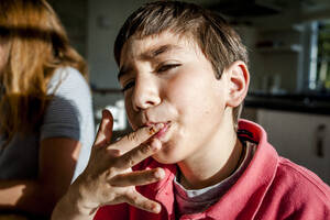 Porträt eines Jungen, der zu Hause seinen Finger ableckt - EGBF00448
