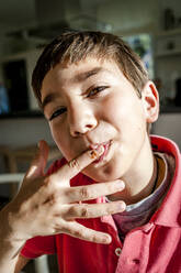 Porträt eines Jungen, der zu Hause seinen Finger ableckt - EGBF00449