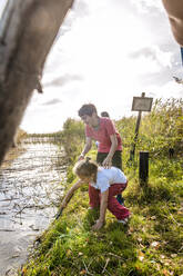 Kinder spielen mit Holzstöcken am Wasserlauf, Darss, Mecklenburg-Vorpommern, Deutschland - EGBF00463