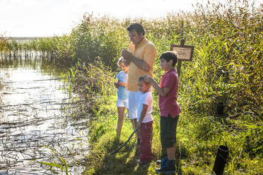 Father and children standing at water course, Darss, Mecklenburg-Western Pomerania, Germany - EGBF00465