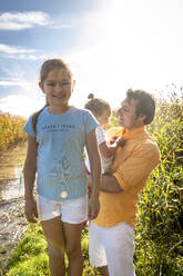 Portrait of a smiling girl with her family at a water course, Darss, Mecklenburg-Western Pomerania, Germany - EGBF00469