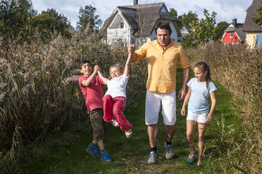 Father with three children walking on a rural path, Darss, Mecklenburg-Western Pomerania, Germany - EGBF00473