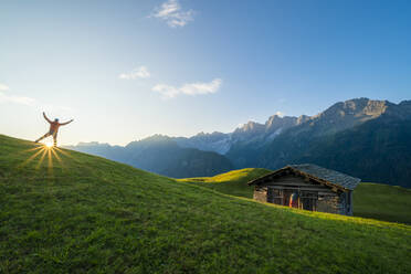 Rückansicht eines jubelnden Mannes in der Morgendämmerung, Tombal, Soglio, Schweiz - CAVF65981