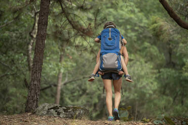 Mutter wandert mit ihrem Kleinkind im Rucksack in einem Wald bei Huasca de Ocampo, Mexiko - CAVF66048