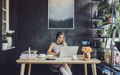 Geschäftsfrau, die im Büro zu Hause am Laptop arbeitet - CAVF66137