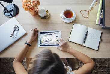 Overhead view of businesswoman using tablet computer while sitting at table - CAVF66148