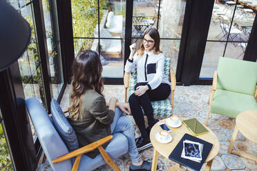 High angle view of colleagues talking in cafe - CAVF66178