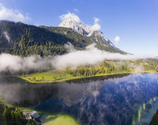 Deutschland, Bayern, Mittenwald, Dichter Nebel schwebt über dem Ferchensee mit Wettersteinspitzen im Hintergrund - SIEF09232