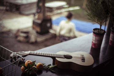 Akustische Gitarre liegt auf dem Tisch mit frisch gepflücktem Obst über dem Kamin - CAVF66299
