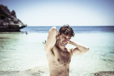 Hübscher Mann streckt sich und lächelt am schönen blauen Strand in Australien - CAVF66309