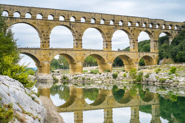 Der Pont du Gard spiegelt sich am frühen Morgen im Fluss Gard, Frankreich - CAVF66356