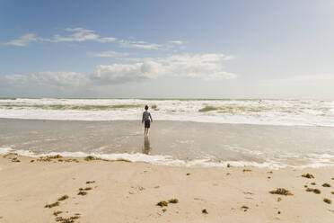 Rückansicht eines am Strand stehenden Jungen gegen den Himmel an einem sonnigen Tag - CAVF66538