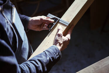 Mittelteil eines Zimmermanns, der in der Werkstatt ein Holzbrett ausmisst - CAVF66590