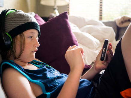 Junge benutzt Smartphone, während er zu Hause Musik hört - CAVF66620