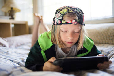 Junge benutzt Tablet-Computer, während er zu Hause auf dem Bett liegt - CAVF66622