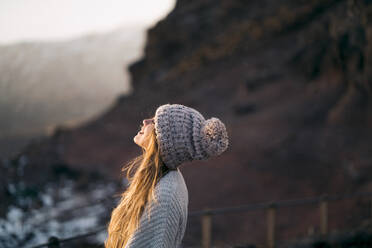 Side view of smiling woman in warm clothing - CAVF66637