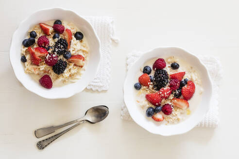 Schalen mit frischem veganen Müsli mit verschiedenen Beeren, Johannisbeeren und Mandelmilch - EVGF03519