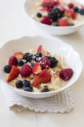 Schalen mit frischem veganen Müsli mit verschiedenen Beeren, Johannisbeeren und Mandelmilch - EVGF03521