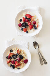 Schalen mit frischem veganen Müsli mit verschiedenen Beeren, Johannisbeeren und Mandelmilch - EVGF03522