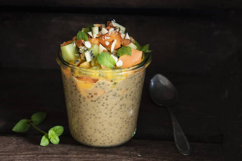 Veganer Pudding im Glas mit Chia, Mandelmilch, Kaki, Kiwi, Papaya, Passionsfrucht und Mandeln - EVGF03529